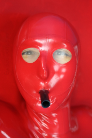 Attached made to measure latex mask in red 0.4mm latex , equipped with transparent latex lens and attached breathing hose . The vacbed remains totally airtight .